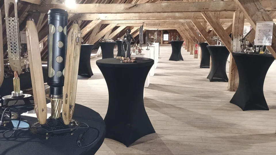 Vue d’ensemble d’une exposition de sculptures sous une charpente en bois