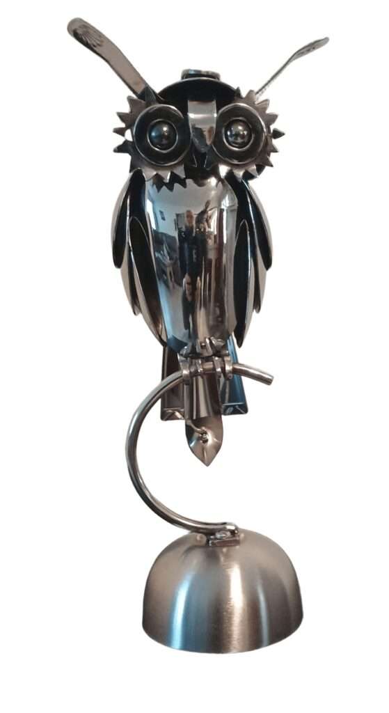Sculpture chouette en métal recyclé avec yeux expressifs, bec en pièce détournée et plumage stylisé en couverts anciens