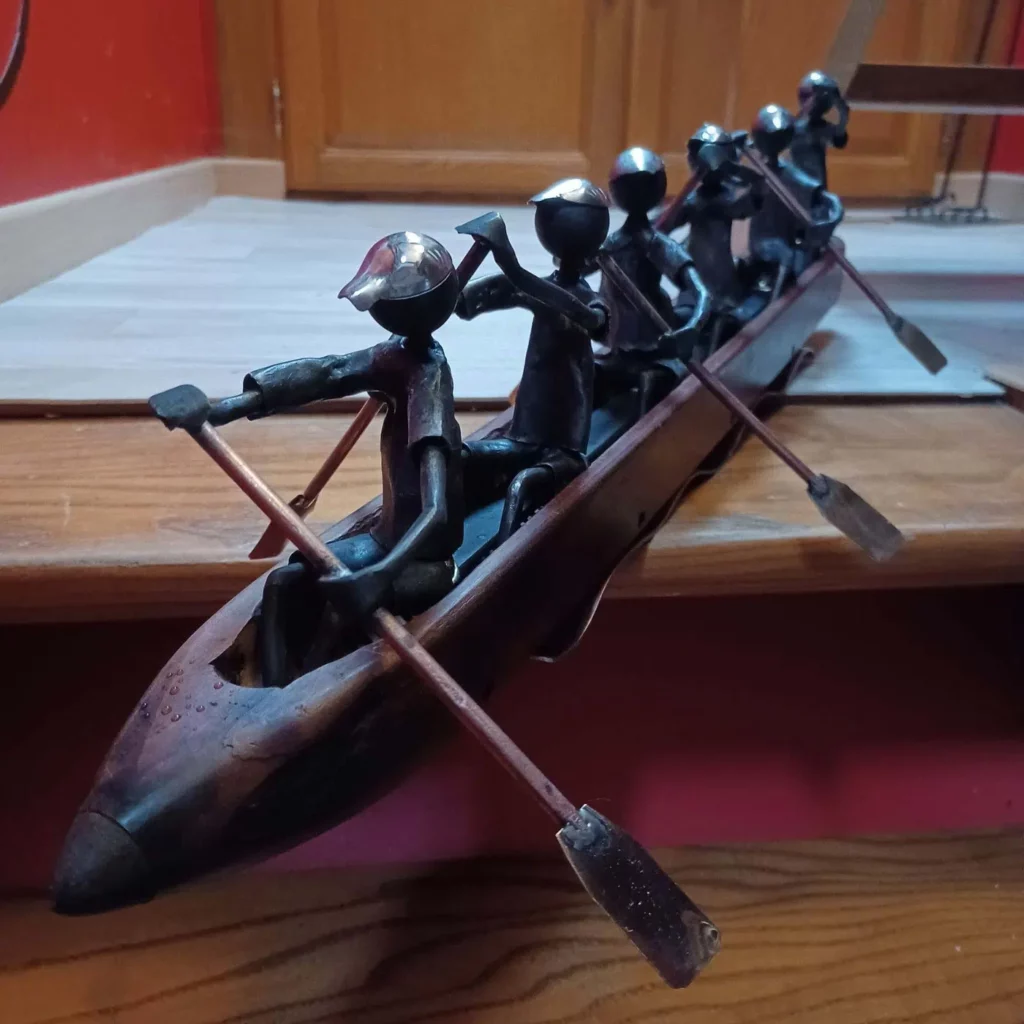 Pirogue en métal recyclé avec six rameurs et détails façonnés à la main
