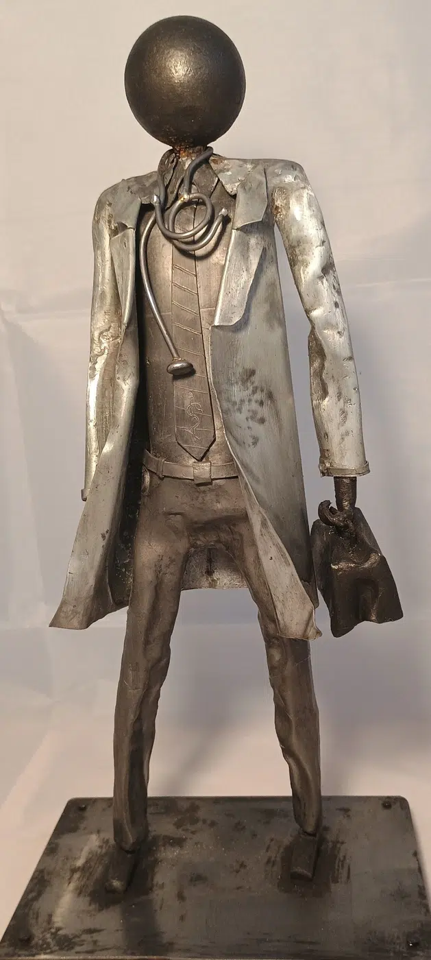 Sculpture médecin en métal recyclé avec blouse stylisée, stéthoscope et détails en cuivre