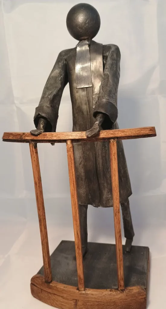 Sculpture avocat en métal recyclé avec robe noire, posture expressive et accessoires juridiques