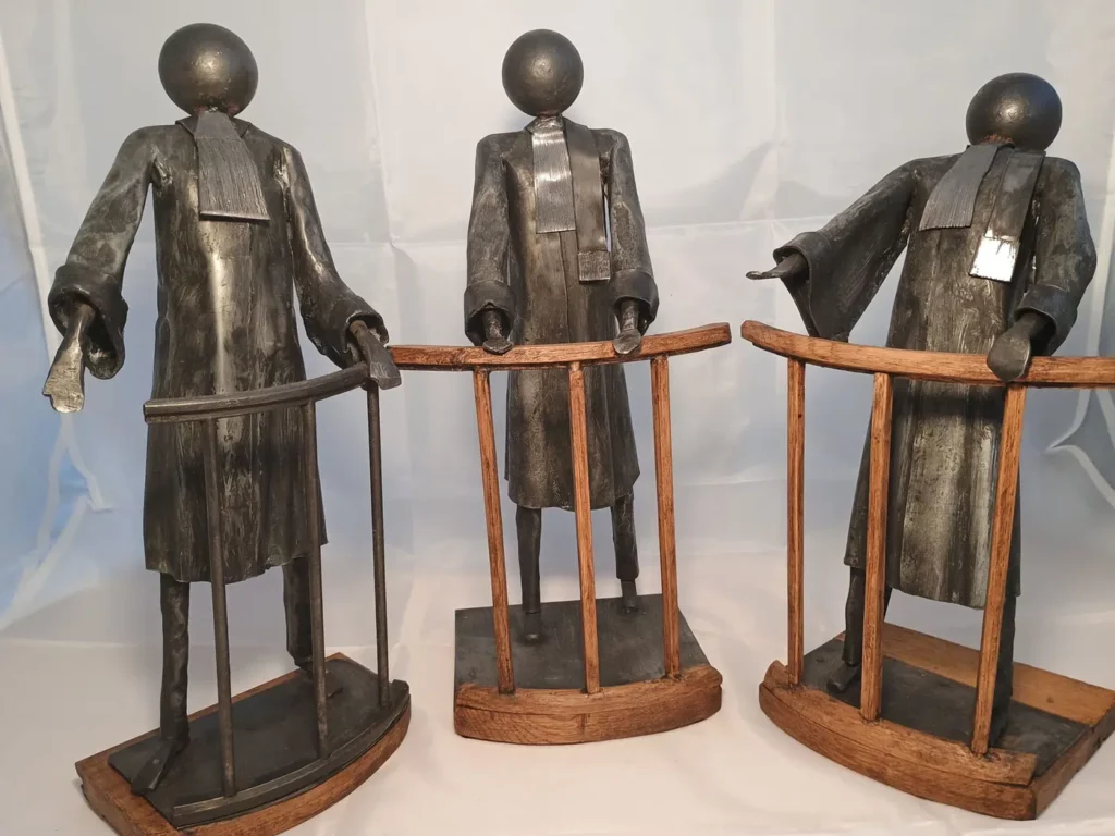 Sculpture avocat en métal recyclé avec robe noire, posture expressive et accessoires juridiques