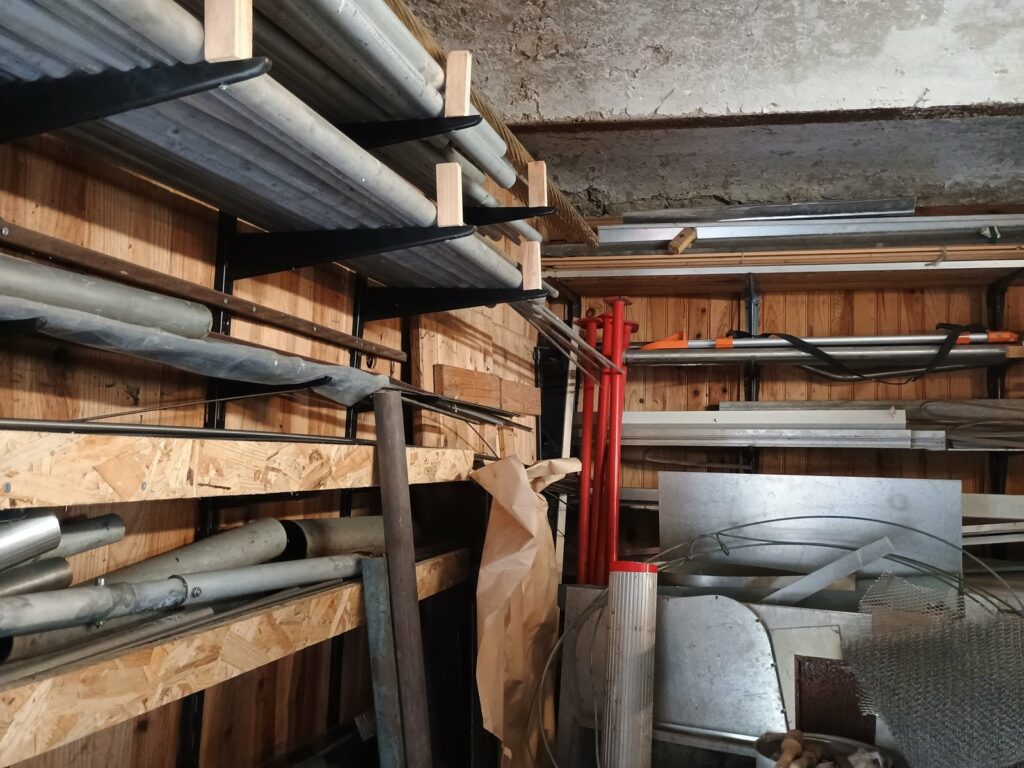 Étagères de profilés et de pièces métalliques récupérées dans l’atelier