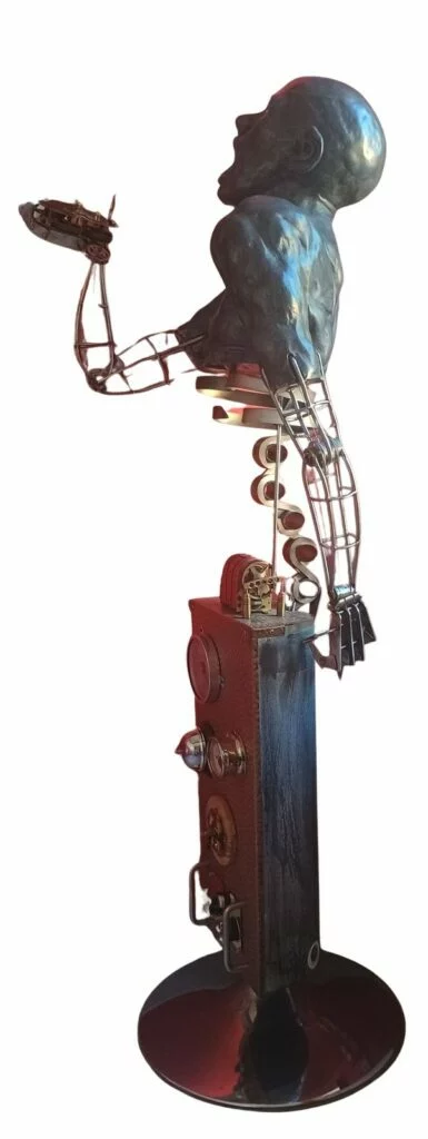Vue latérale de la sculpture La souffrance de l’homme, haute structure mécanique et personnage